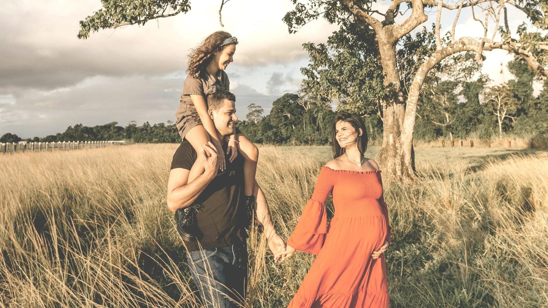 Familia caminando en el campo, con una mujer embarazada