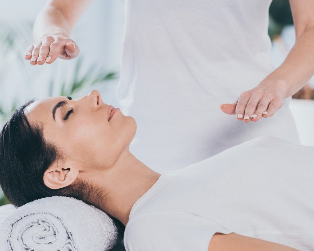 Practitioner holding her hands over a woman during an energy healing session