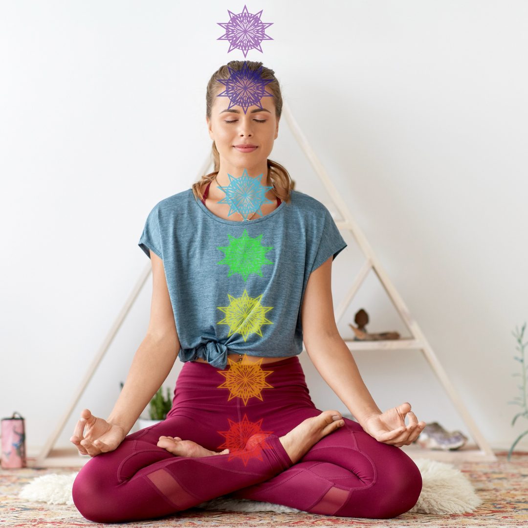 Woman meditating in lotus pose with the seven chakras illustrated along her body