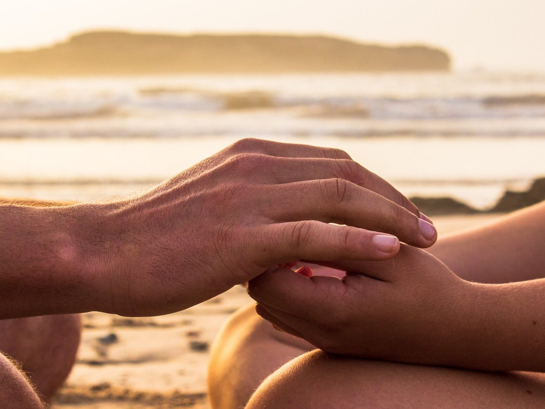Two hands joined at sunset on the beach