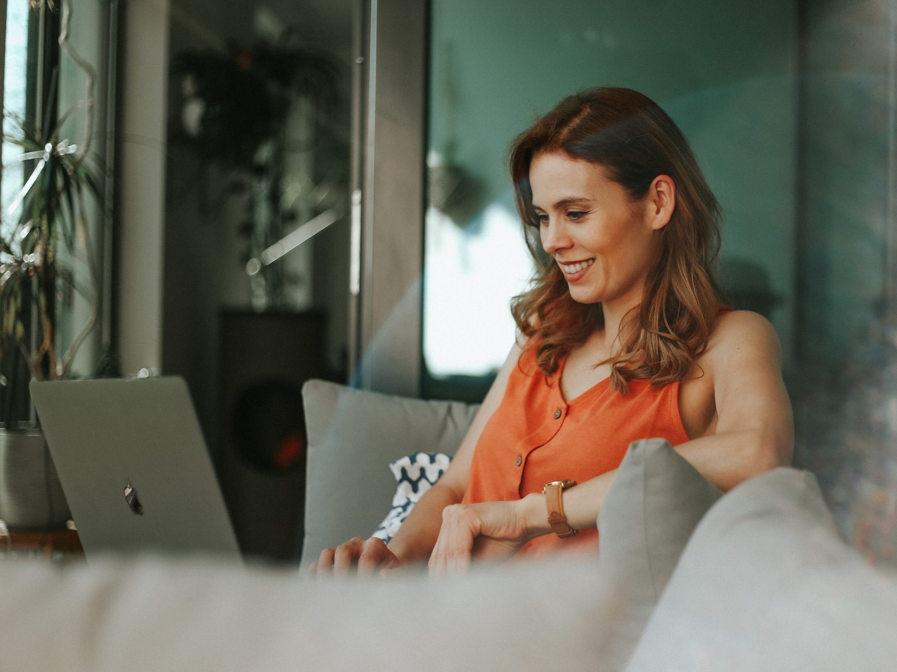Smiling woman working on her laptop from a sofa